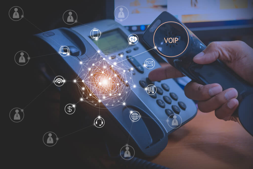 Hand of Man Using Ip Phone With Flying Icon of VoIP Services