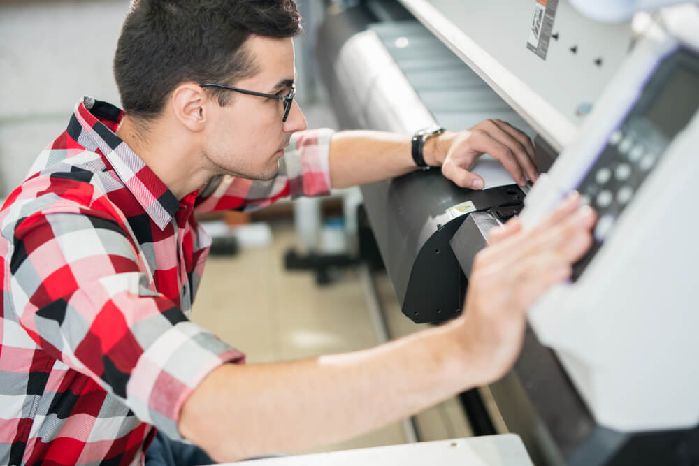 Young Engineer in Shirt Examining Wide Format Printer