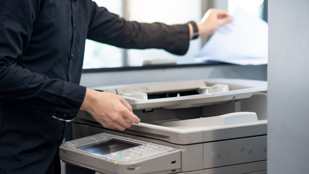 Male Businessman Using Photocopier in Office 
