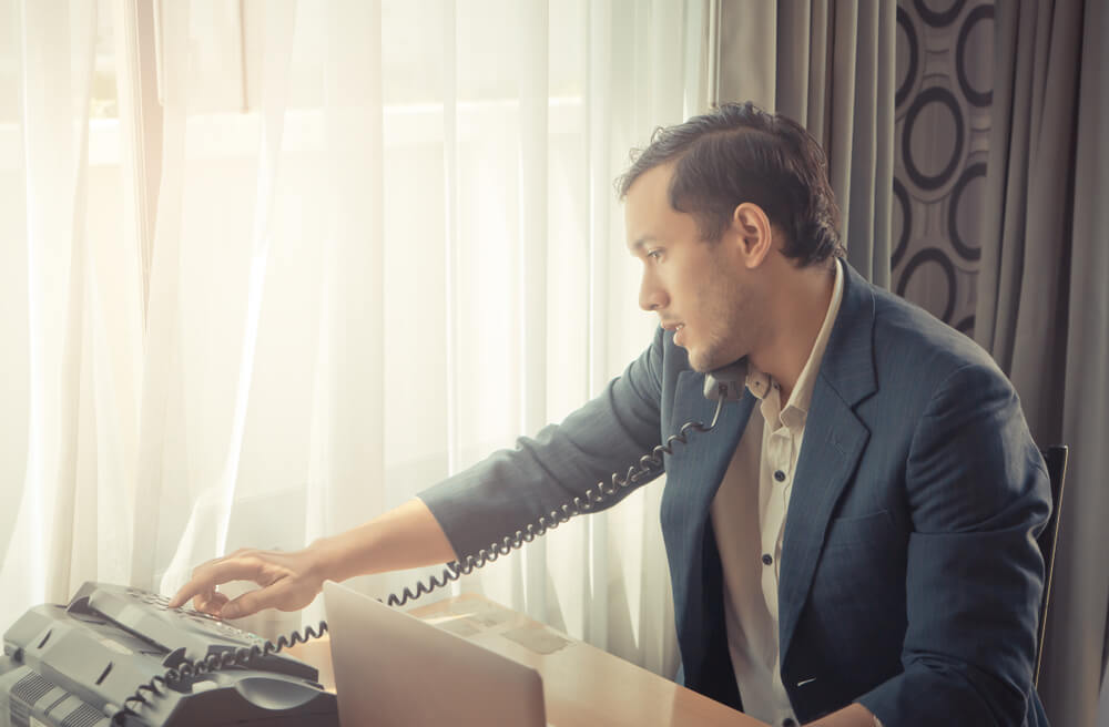 Business Man Is Making Call on Fax Machine Landline on Office Desk for Business Communication Concept.