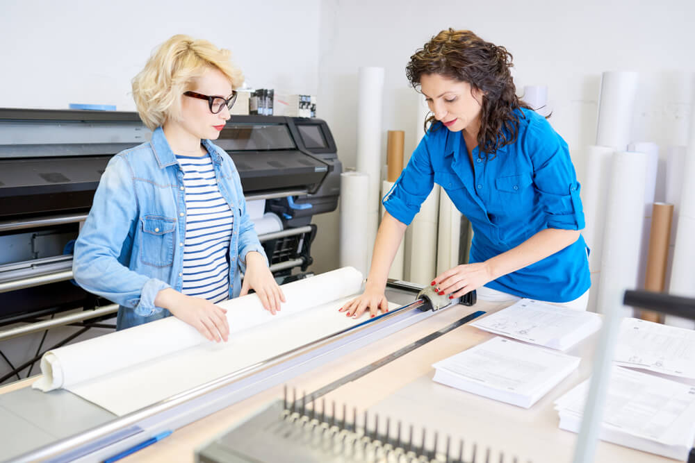 Portrait of Two Modern Young Women Working in Printing Shop or Publishing Company