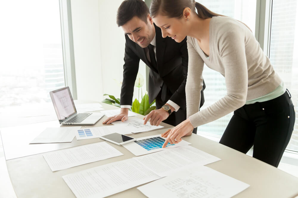 Smiling Professional Designers Working on Project at Office Desk